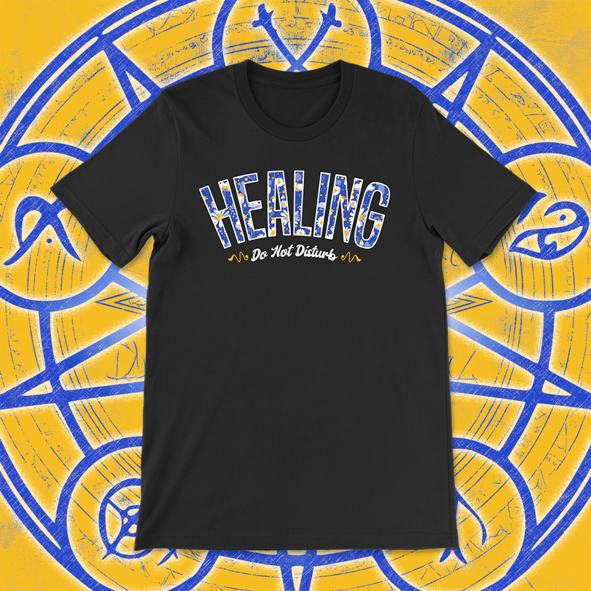 Black unisex t-shirt with the word “HEALING” in blue and white floral print, and “Do Not Disturb” in cursive beneath. Set against a magical yellow and blue background with arcane symbols.