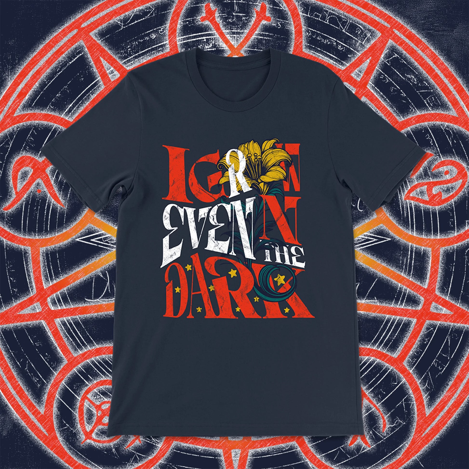 Navy blue unisex t-shirt with the phrase “I Grow Even in the Dark” in stylized red, white, and yellow lettering, adorned with a blooming lily and golden stars. Styled against an arcane, rune-covered background in navy and red.
